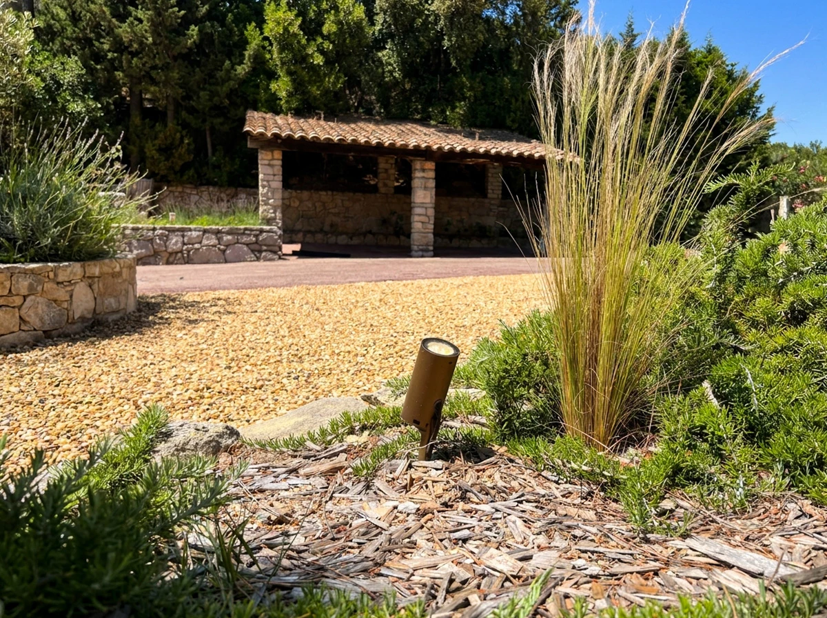 Éclairage extérieur nocturne dans jardin avec borne lumineuse cylindrique noire diffusant lumière blanche chaude