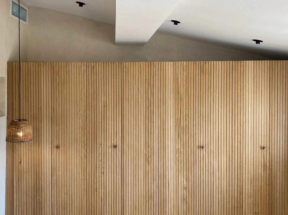 Électricien professionnel travaillant sur installation électrique résidentielle, manipulant multimètre et câblage dans boîtier mural