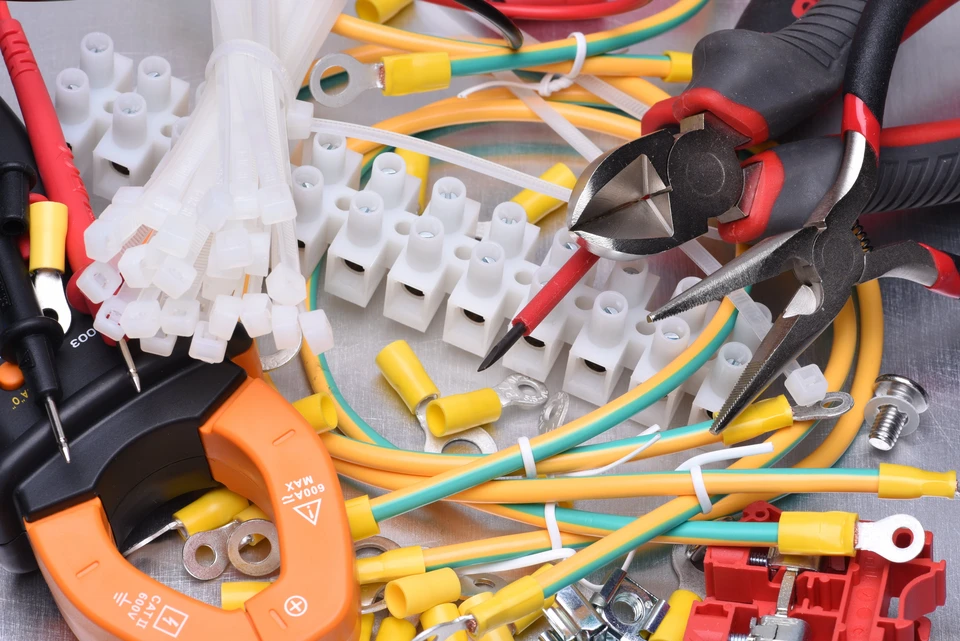Espace de travail d'électricien avec outils et matériel électrique disposés sur surface métallique